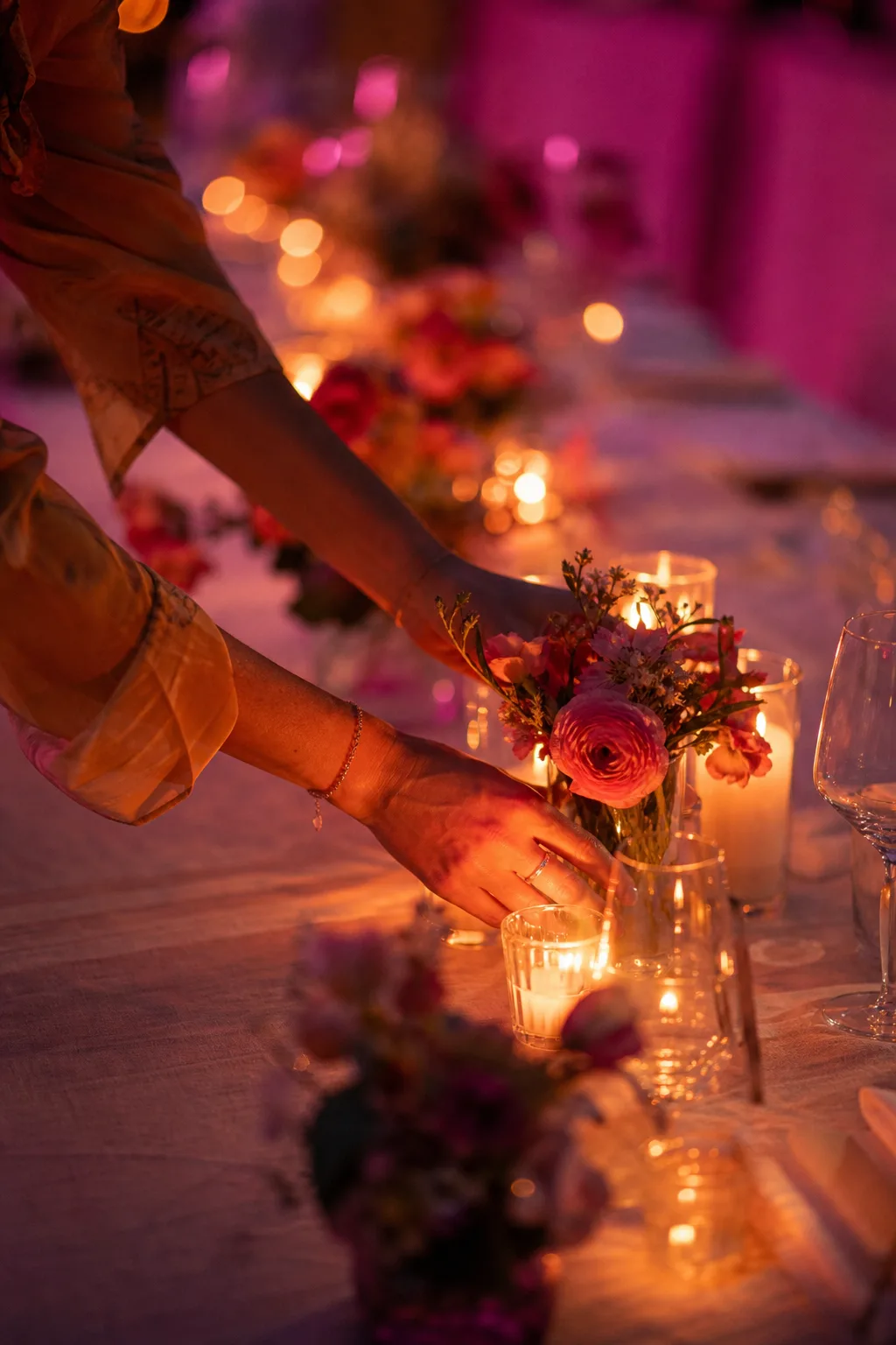 Hands arranging candles and posies on a banquet table
